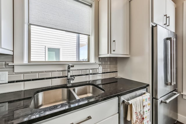 kitchen featuring tasteful backsplash, high end refrigerator, white cabinets, and a sink