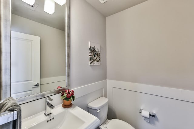 bathroom featuring wainscoting, visible vents, a sink, and toilet