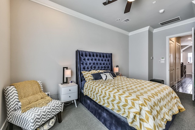 bedroom featuring ornamental molding, dark colored carpet, visible vents, and a ceiling fan