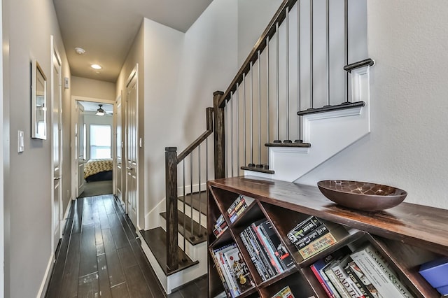 stairway with ceiling fan, baseboards, and wood finished floors