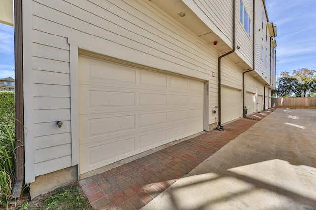 garage featuring fence and decorative driveway