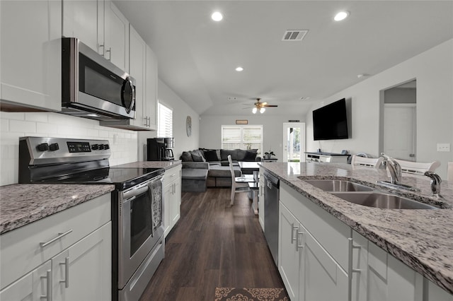 kitchen featuring stainless steel appliances, a sink, visible vents, open floor plan, and light stone countertops