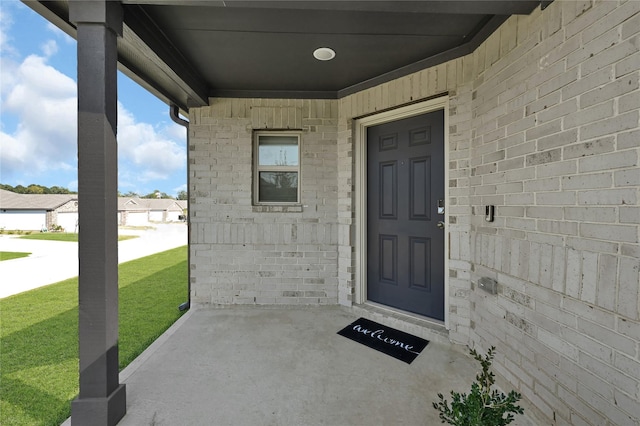 doorway to property featuring a lawn and brick siding