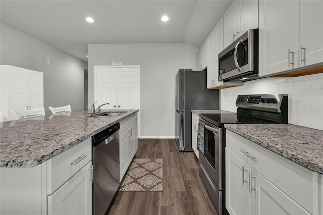 kitchen with light stone counters, a sink, appliances with stainless steel finishes, decorative backsplash, and dark wood-style floors