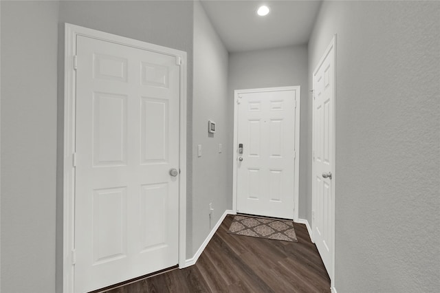 doorway with dark wood-style flooring and baseboards