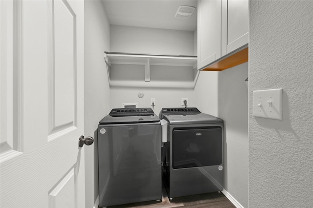 laundry area featuring dark wood finished floors, cabinet space, visible vents, washing machine and dryer, and baseboards