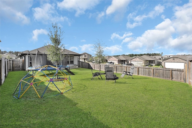 view of yard featuring a trampoline, a residential view, and a fenced backyard