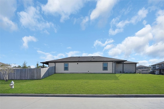 back of house featuring fence and a lawn