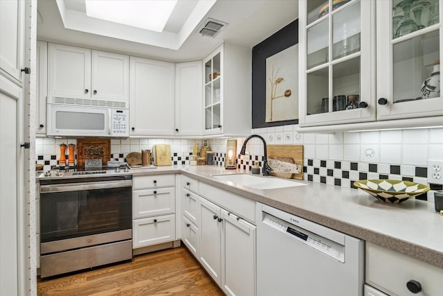 kitchen with white appliances, visible vents, light wood-style flooring, white cabinetry, and a sink