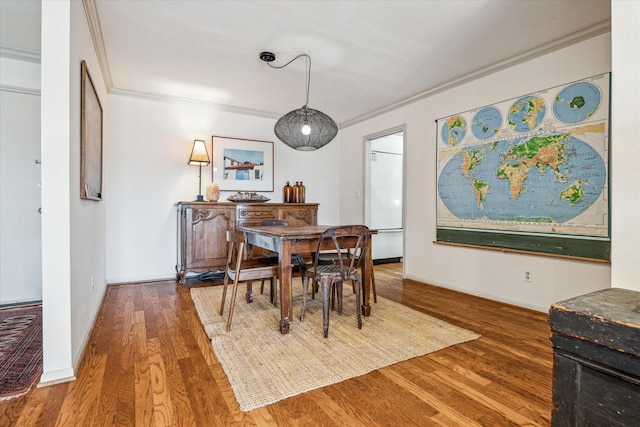 dining space featuring baseboards, ornamental molding, and wood finished floors