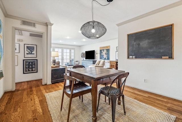 dining room with light wood-style floors, visible vents, and ornamental molding