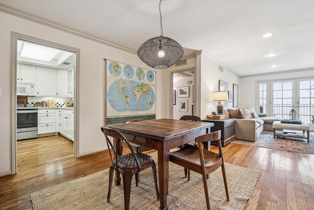 dining room with light wood-style floors, visible vents, a skylight, and ornamental molding