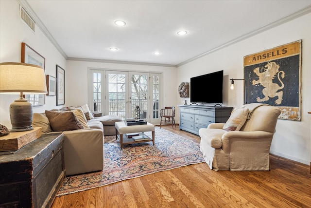 living area with visible vents, wood finished floors, and ornamental molding