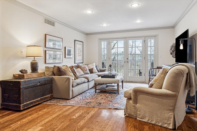 living area with light wood finished floors, french doors, ornamental molding, and visible vents