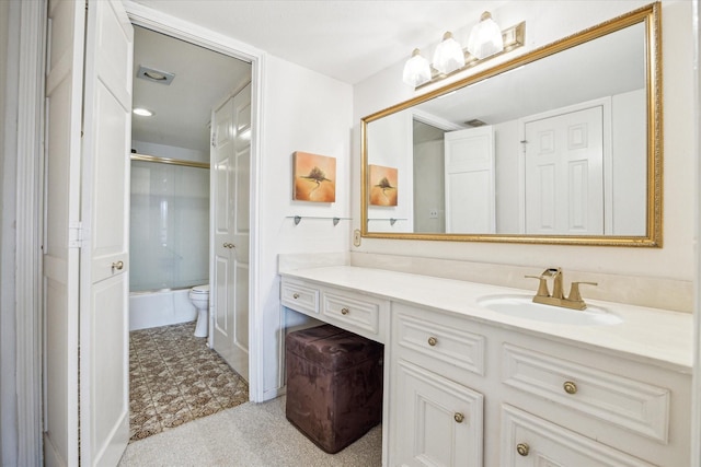 bathroom featuring combined bath / shower with glass door, vanity, and toilet