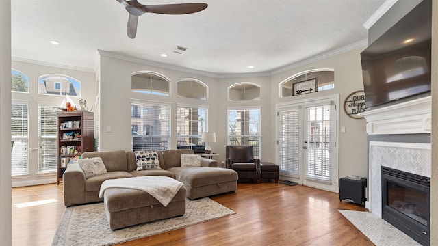 living room with a fireplace with flush hearth, visible vents, crown molding, and wood finished floors