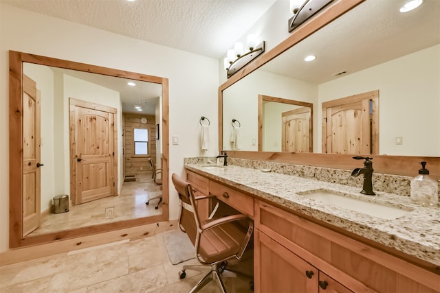 full bath featuring a walk in shower, a sink, a textured ceiling, and double vanity