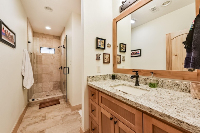 full bath with a stall shower, vanity, visible vents, and baseboards