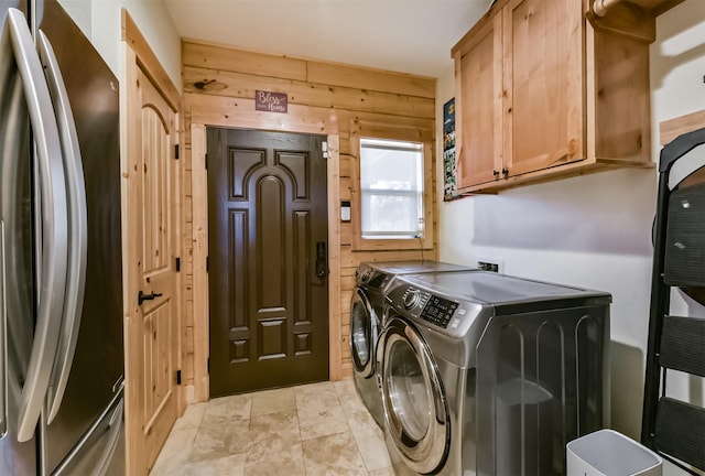 washroom featuring wood walls, washer and clothes dryer, and cabinet space