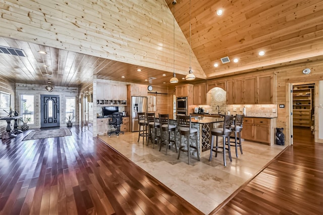 dining space with light wood-type flooring, wooden ceiling, visible vents, and a high ceiling