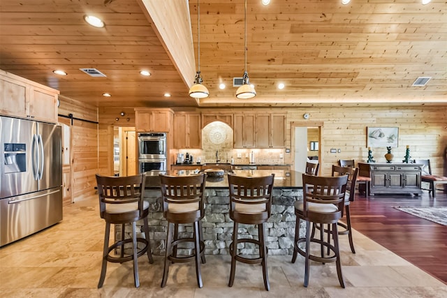 kitchen featuring a barn door, wooden walls, recessed lighting, stainless steel appliances, and wood ceiling