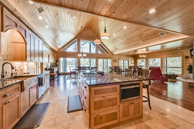 kitchen featuring wood ceiling, appliances with stainless steel finishes, open floor plan, a kitchen bar, and a notable chandelier