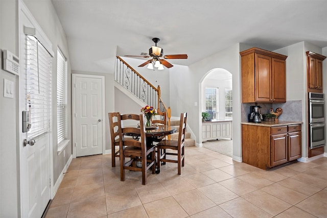 dining room with light tile patterned floors, ceiling fan, stairs, and baseboards