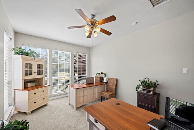 home office with a ceiling fan, visible vents, and light colored carpet