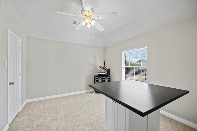 unfurnished office with a ceiling fan, light colored carpet, visible vents, and baseboards