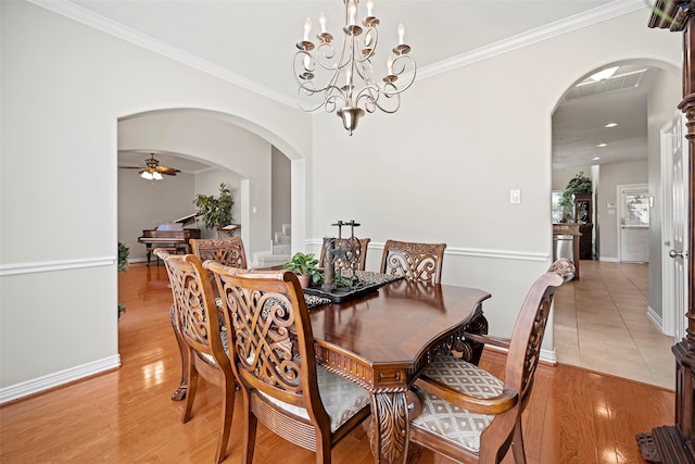 dining area featuring ornamental molding, arched walkways, light wood-style flooring, and ceiling fan with notable chandelier