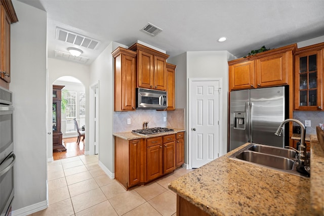 kitchen featuring arched walkways, visible vents, stainless steel appliances, and a sink