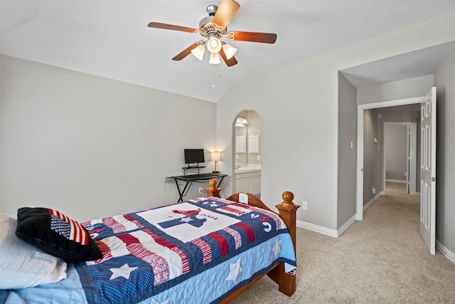 bedroom with lofted ceiling, baseboards, arched walkways, and light colored carpet