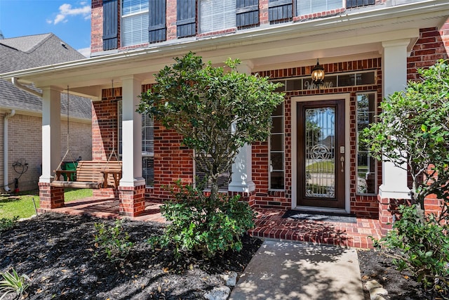 entrance to property with covered porch and brick siding