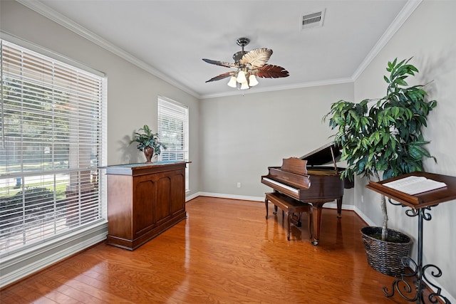 sitting room with a ceiling fan, visible vents, crown molding, and light wood finished floors