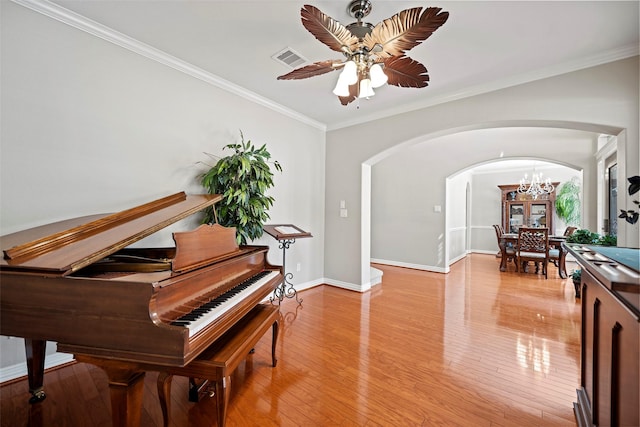 living area with light wood finished floors, baseboards, visible vents, arched walkways, and crown molding