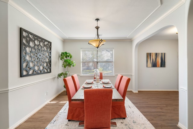 dining area featuring arched walkways, ornamental molding, baseboards, and wood finished floors