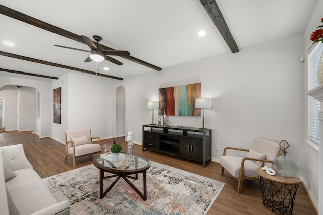 living area featuring baseboards, arched walkways, a healthy amount of sunlight, and wood finished floors