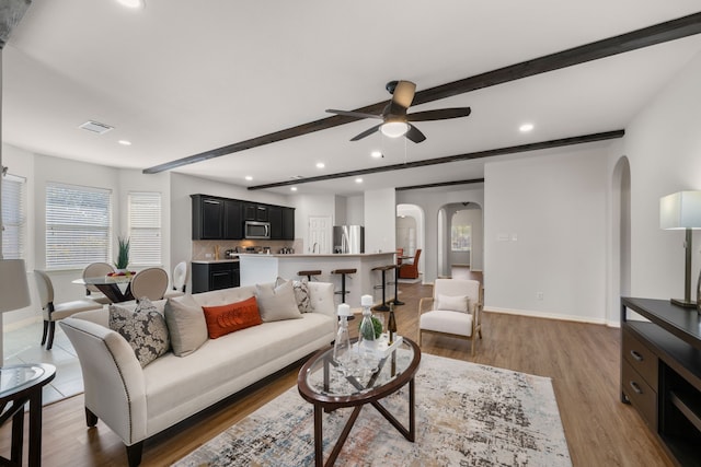 living room with baseboards, visible vents, arched walkways, and beamed ceiling