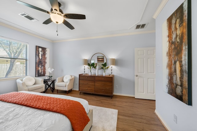 bedroom with visible vents, crown molding, baseboards, and wood finished floors