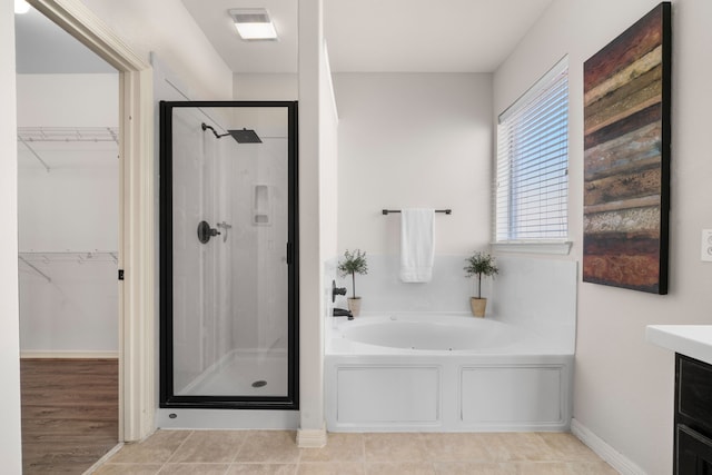 bathroom with vanity, visible vents, a stall shower, a walk in closet, and a garden tub