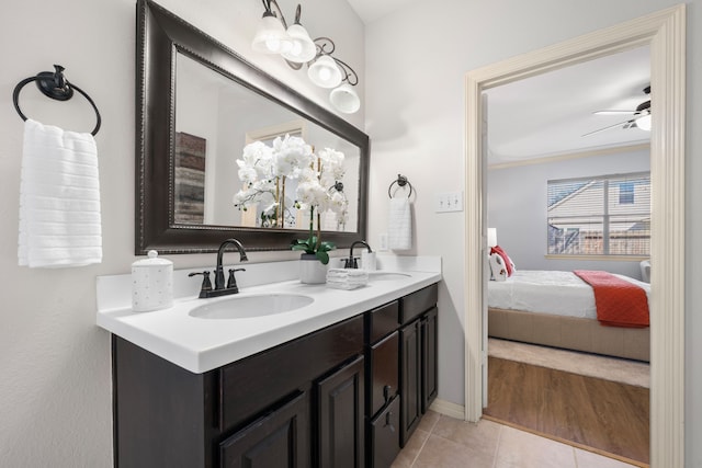 ensuite bathroom with ceiling fan, tile patterned floors, double vanity, and a sink