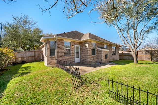 back of property with a yard, a patio area, brick siding, and a fenced backyard