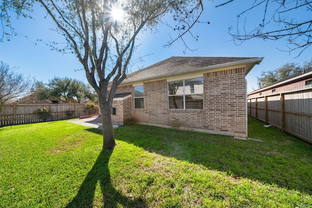 back of property with brick siding, a patio area, a lawn, and a fenced backyard