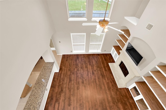 unfurnished living room with a ceiling fan, visible vents, and wood finished floors