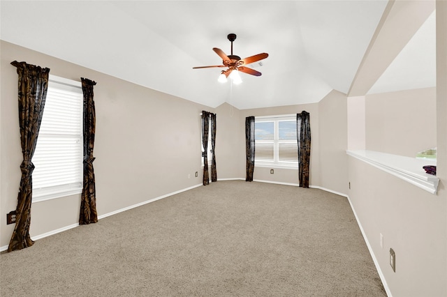 carpeted empty room featuring vaulted ceiling, a ceiling fan, and baseboards