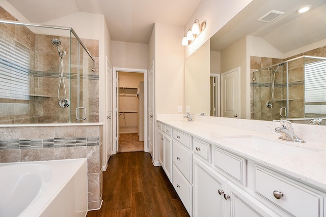 full bath with lofted ceiling, a sink, wood finished floors, visible vents, and a stall shower