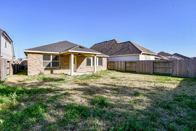 rear view of property featuring brick siding, a lawn, and a fenced backyard