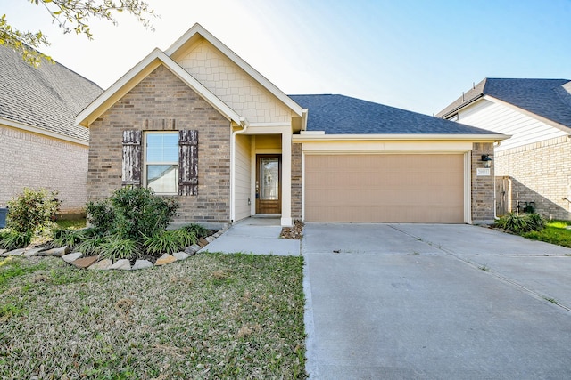 view of front facade with roof with shingles, driveway, brick siding, and an attached garage