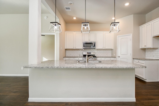 kitchen featuring light stone counters, dark wood-style flooring, a sink, visible vents, and appliances with stainless steel finishes