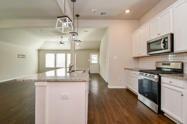 kitchen featuring light stone counters, stainless steel appliances, a sink, visible vents, and tasteful backsplash